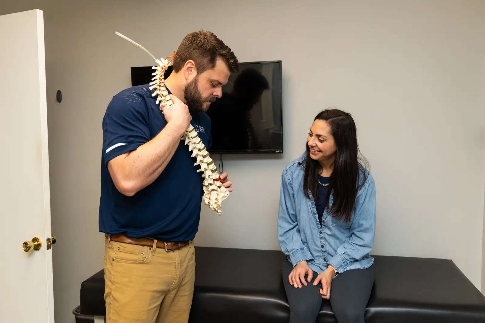 Dr. Kyle Pelphrey explaining findings to a patient with a spine model at Pelphrey Chiropractic in Lexington, KY